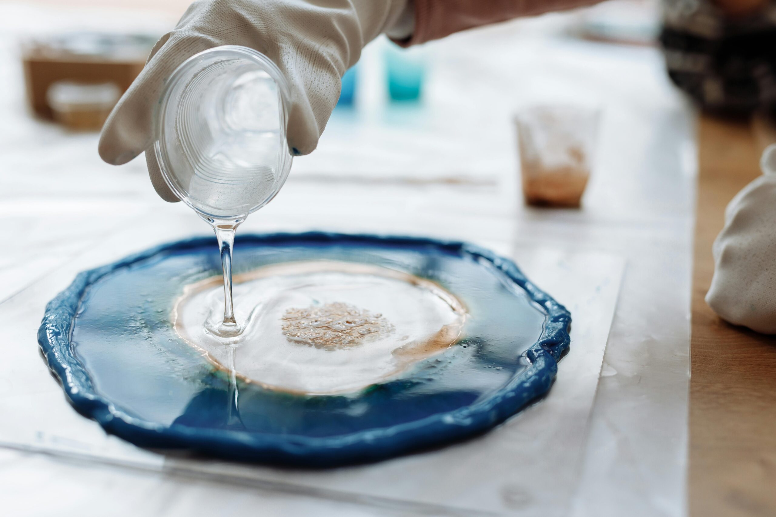 Designing My First Epoxy Table: Lessons Learned 2 Detailed image of resin art being created with gloves and a plastic cup.